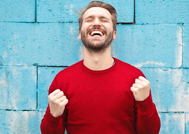 Homme souriant devant un mur| Orthodontie des Laurentides à St Jérôme